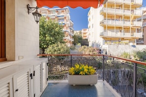 A balcony with a potted plant, a tiled floor, and a view of multi-story buildings. - Sanremo la Mimosa by Wonderful Italy (Sanremo)