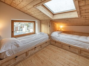 A cozy room with two beds, a skylight, and a window overlooking a town. - Casa Poligrafica 2, exclusive and comfortable (Cortina d´Ampezzo)