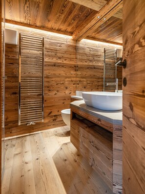 A modern bathroom with wooden paneling, a large mirror, and a vessel sink. - Casa Poligrafica 2, exclusive and comfortable (Cortina d´Ampezzo)