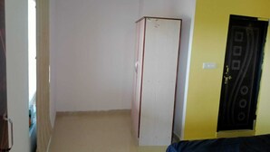 A room with a white wardrobe, a yellow wall, and a black door with a circular design. - Abuzz Oxfordcaps Genesis Genome Valley (Shamirpet)