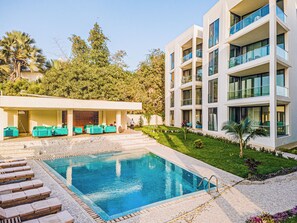 Ein modernes Gebäude mit Pool, Sitzgelegenheiten im Freien und einem gepflegten Garten.