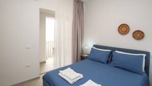 A bedroom with a bed, curtains, a bedside table with a lamp, and wall decor.