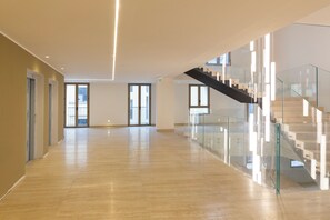 Ein geräumiger, moderner Innenraum mit Holzboden, Glasgeländern und einer Treppe.