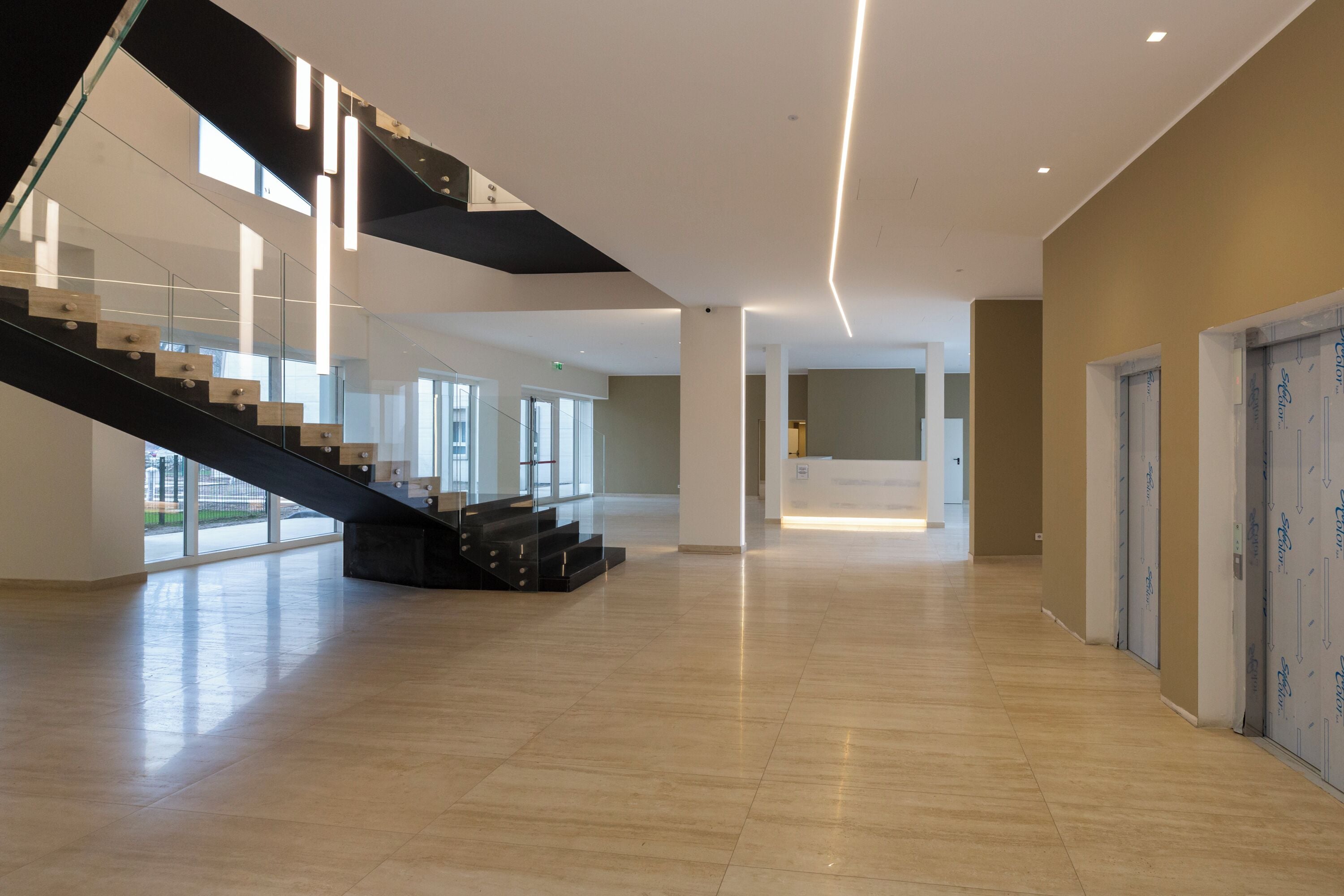 A spacious interior with a modern staircase, large windows, and a clean, minimalist design.