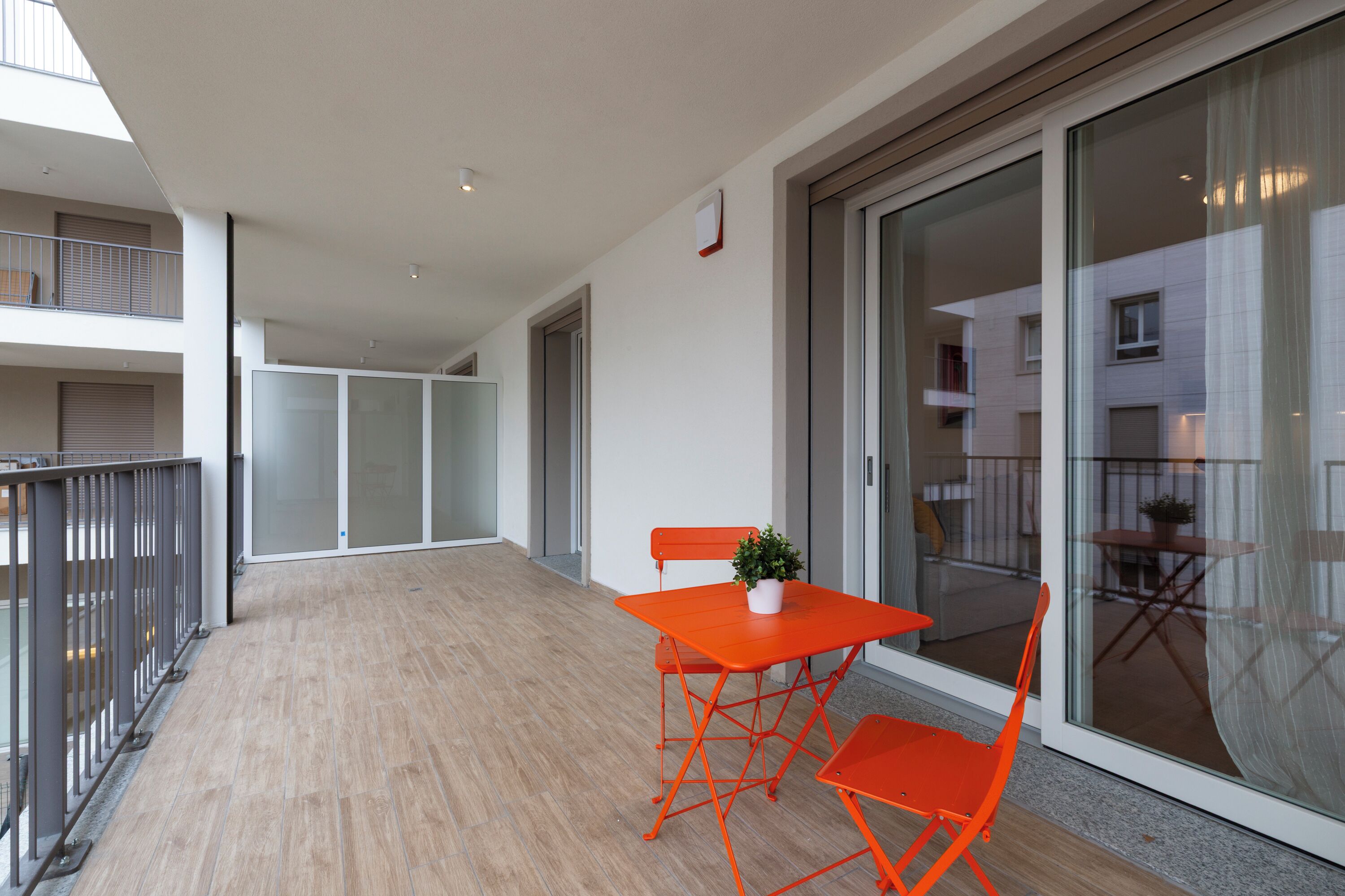 Ein Balkon mit Holzboden, einem Tisch und zwei Stühlen sowie einem Blumentopf.