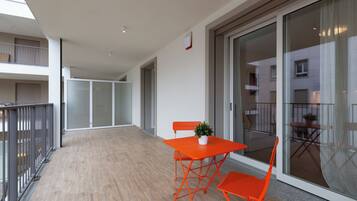 Ein Balkon mit Holzboden, einem Tisch und zwei Stühlen sowie einem Blumentopf.