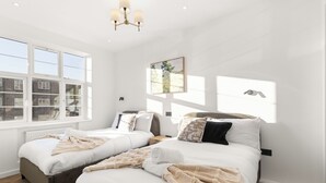 A hotel room with two beds, large windows, a chandelier, and a painting on the wall. - Apartment - Sleeps 8 - Golders Green 10 Mins (London)