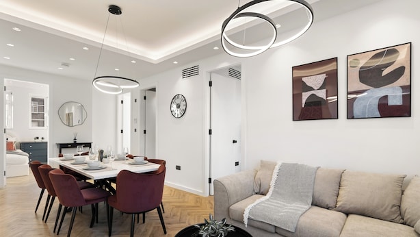 A modern living room with a sofa, a dining area with a table and chairs, and abstract wall art. - Apartment - Sleeps 8 - Golders Green 10 Mins (London)