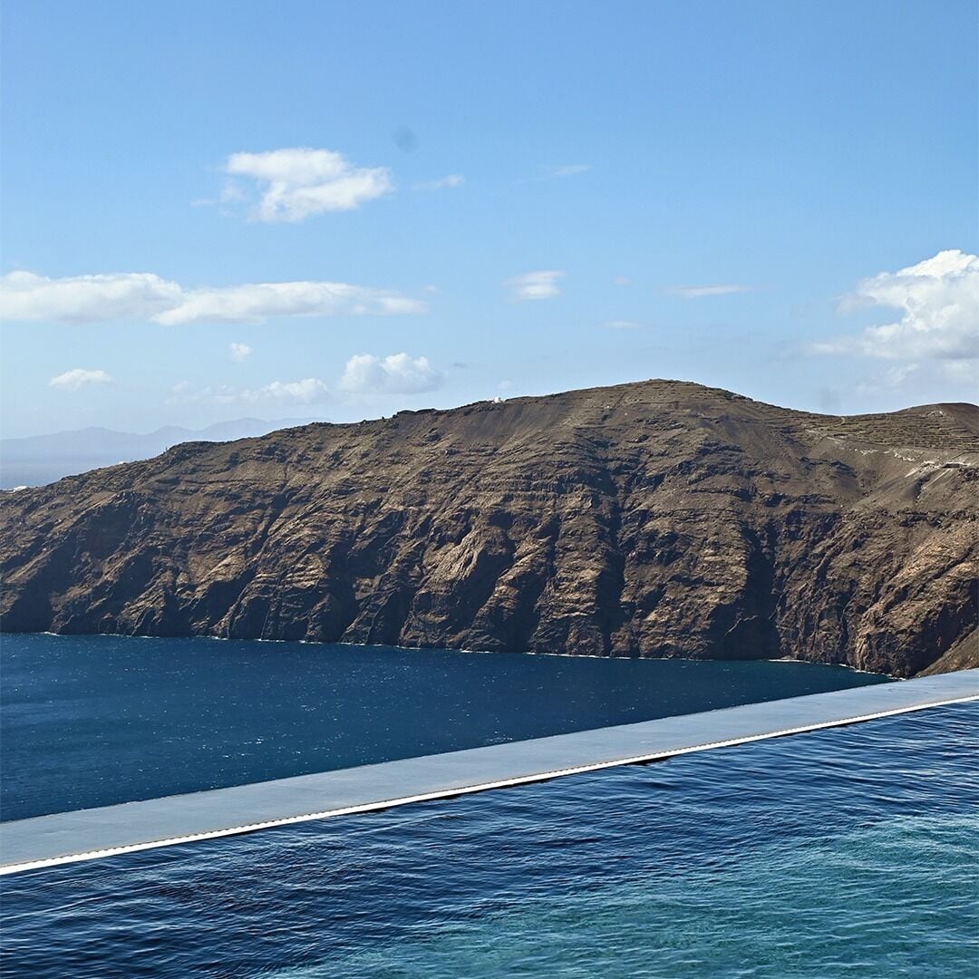 A coastal landscape with a rocky cliff and a clear blue sky.