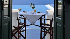An open door leading to a table set with breakfast items and a view of the sea. - Anastasis Apartments and Spa (Santorini)