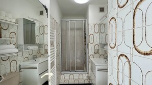 Een badkamer met douche, toilet, wastafel en handdoekrekken.
