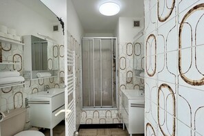 Ein Badezimmer mit Dusche, Toilette, Waschbecken und Handtuchhaltern.