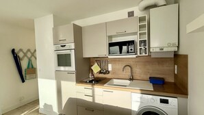 Een kleine keuken met een magnetron, oven, spoelbak en wasmachine.