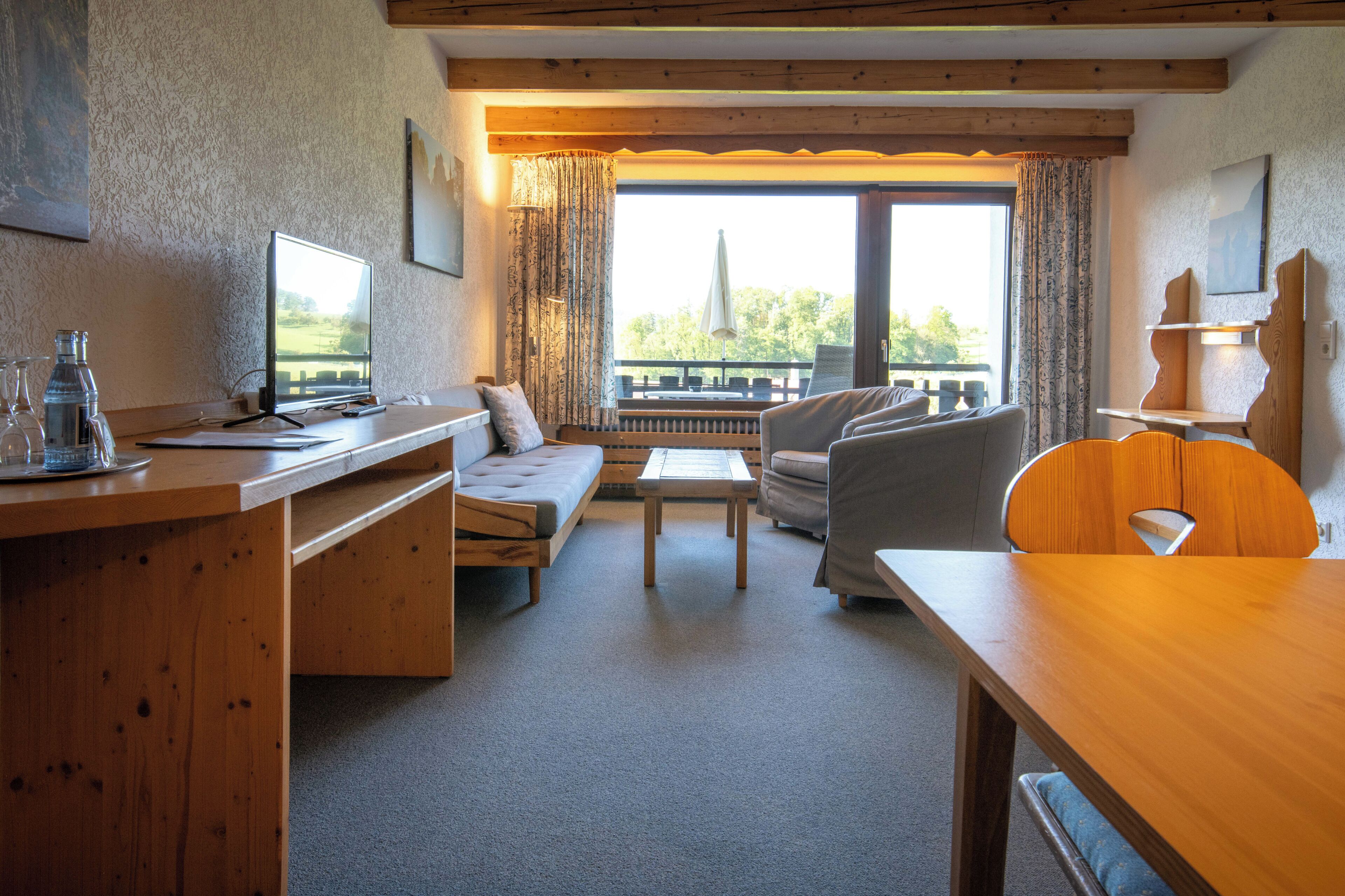 Une pièce chaleureuse avec un bureau en bois, un canapé, une petite table et une fenêtre avec des rideaux.