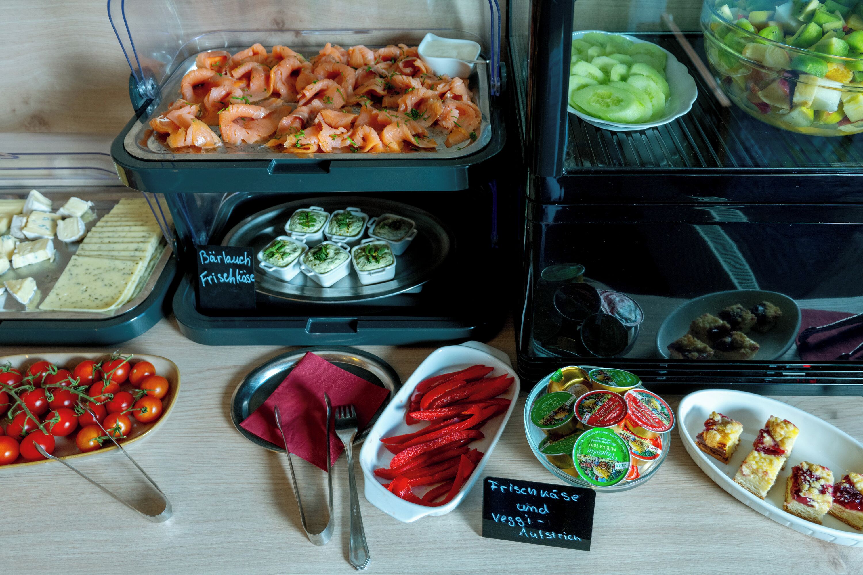 A buffet with various food options including salmon, vegetables, and cheese.