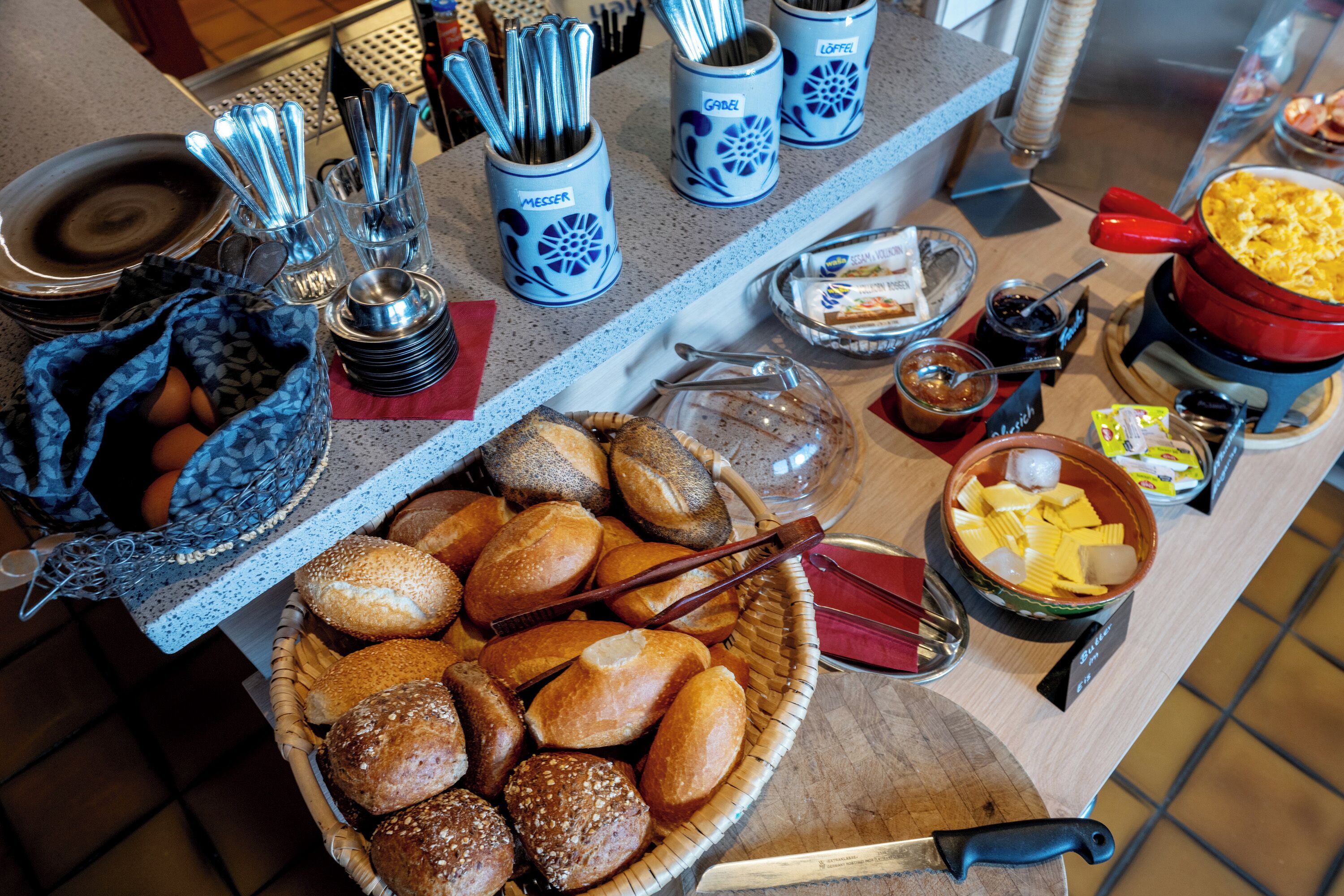 Ein Frühstücksbuffet mit verschiedenen Brotsorten, Backwaren und Beilagen.
