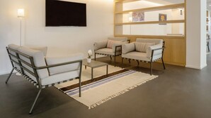 En moderne stue med sofa, lænestole, sofabord og et tv ophængt på væggen.