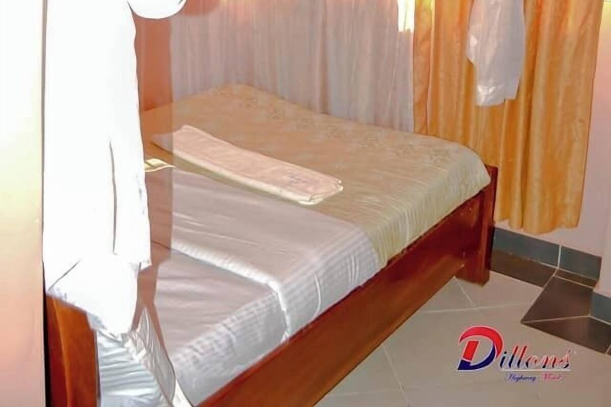 A bedroom with a canopy bed, a bedside table, and a window with curtains.