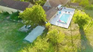 Vista aérea de una propiedad con piscina, terraza cubierta y abundante vegetación.