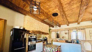 Una cocina rústica con vigas de madera, un refrigerador negro, una estufa y una mesa de comedor con mantel de lunares.
