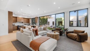 Ein modernes Wohnzimmer mit Küche, Sitzecke und großen Fenstern.