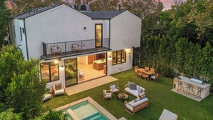 Ein modernes, zweistöckiges Haus mit Balkon, Swimmingpool und gepflegtem Garten.