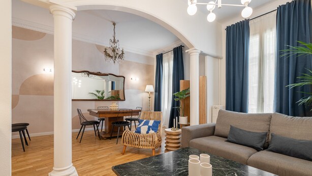 Un salon comprenant une table basse en marbre, un canapé et un coin repas avec une table et des chaises.