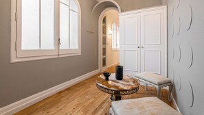 Un couloir avec une table ronde, un banc et une porte dotée d’un miroir.