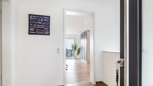 En hall med en skylt som visar olika platser i New York, trägolv och en dörr med en nyckelring.