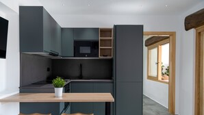 A modern kitchen with dark cabinetry, a microwave, and a small table with two stools. - Holiday Apartment 'El Alcaidón 1' with Wi-Fi and Air Conditioning (Tías)