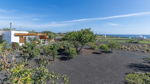 A modern house with a garden, a view of the sea, and a clear sky. - Holiday Apartment 'El Alcaidón2' with Wi-Fi and Air Conditioning (Tías)