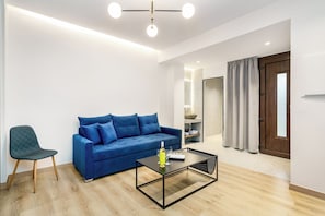 Ein modernes Wohnzimmer mit einem blauen Sofa, einem grünen Sessel und einem Glastisch.