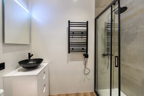 A modern bathroom with a black basin, a glass shower enclosure, and a towel rack. - Modern, fully equipped studio with balcony in the centre of Madrid Tempory  HOR42DA (Madrid)