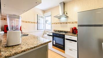 Una cocina moderna con encimeras de granito, horno empotrado, refrigerador de acero inoxidable y ventana con vistas.
