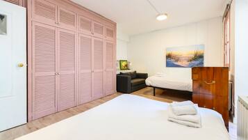 A bedroom with a large bed, a wardrobe, a sofa, and a painting on the wall.