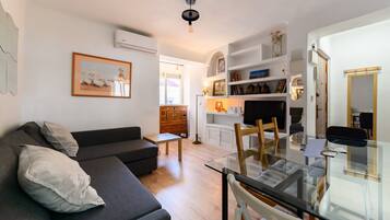 Una sala de estar moderna con una mesa de comedor de vidrio, un sofá oscuro y una chimenea.