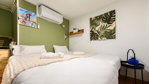 A neatly made bed with white linens, a small bedside table with a blue vase, and a wall-mounted air conditioner. - (SVF1304) Cozy Studio in the Center of Madrid (Madrid)