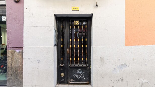 A black door with a number 13 sign, a small window, and some graffiti on the wall. - (SVF1304) Cozy Studio in the Center of Madrid (Madrid)