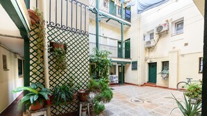 A courtyard with potted plants, a bicycle, and a building with balconies. - (SVF1304) Cozy Studio in the Center of Madrid (Madrid)