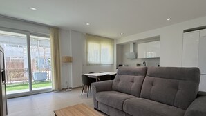 Ein modernes Wohnzimmer mit einem grauen Sofa, einem Holztisch und einem Essbereich mit Tisch und Stühlen.