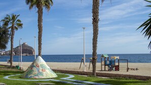 Ein Strand mit Palmen, einem Spielplatz und Blick auf den Ozean.