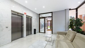 A lobby with marble flooring, two elevators, a sofa, a small table, and a potted plant. - M (SAM12) Fantastic one bedroom apartment in Madrid (Madrid)