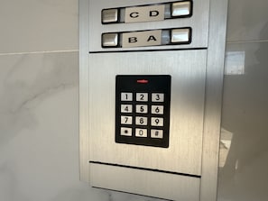 Painel de comandos de elevador metálico, com teclado numérico e botões de seleção de andar.