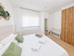 A modern bedroom with a large bed, a wooden wardrobe, a bench, and a mirror. - Apartment 65A · Oceanfront with Private Terrace (Aguilas)