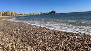 Une plage de galets offrant une vue dégagée sur la mer et les bâtiments situés au loin.
