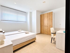 A modern bedroom with two beds, a wooden wardrobe, a desk, and a chair. - Home 65E - Oceanfront with Private Terrace (Aguilas)