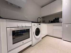 A modern kitchen with a built-in oven, a washing machine, and a microwave. - Home 65F - Beachfront with Private Terrace (Aguilas)