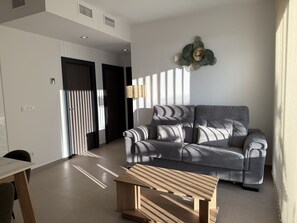 A modern living room with a grey sofa, a wooden coffee table, and a decorative wall piece. - Home 65F - Beachfront with Private Terrace (Aguilas)
