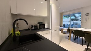 A modern kitchen with white cabinets, a black countertop, and a dining area with a table and chairs. - Home 65F - Beachfront with Private Terrace (Aguilas)