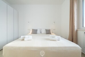 Ein modernes Hotelzimmer mit einem großen Bett, zwei Nachttischen und einem Fenster mit Vorhängen.